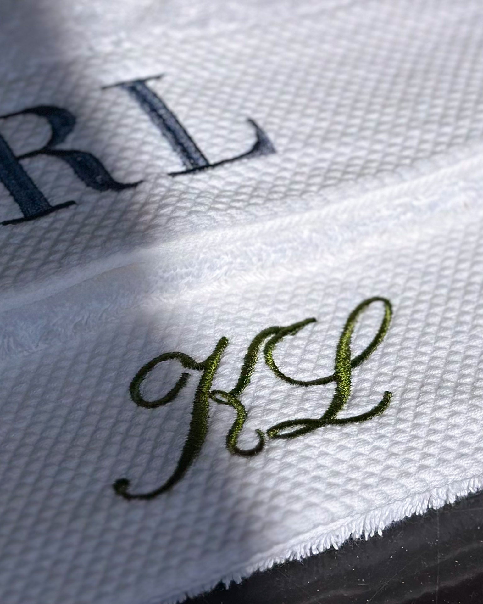 Close-up of embroidered initials on a white towel background